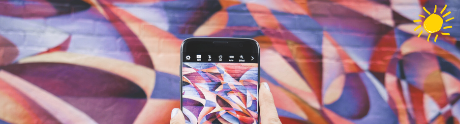 Hands holding an iphone take a picture of a brightly-colored painted wall