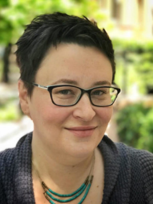Lauren Jost headshot, woman with light skin, short dark hair, and glasses
