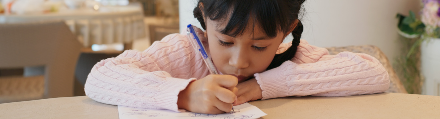 Girl drawing with pen while seated at table